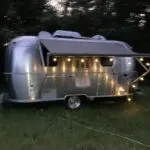 A silver trailer with lights on the side of it.